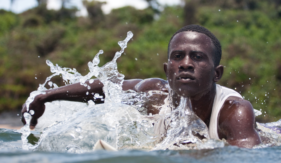 Benjamin McCrumuda has the uncanny ability to summon the seas.  If the ocean goes dormant for too long, he simply slaps the water and bellows out “Kway-Pu-Na!”  This phrase translates to “big sea wave come” in Benjamin’s native tongue of Vai and when he asks, the ocean answers. Photo: Brody/<a href=\"http://www.surfresource.org/\" target=_blank>SurfResource.org</a>